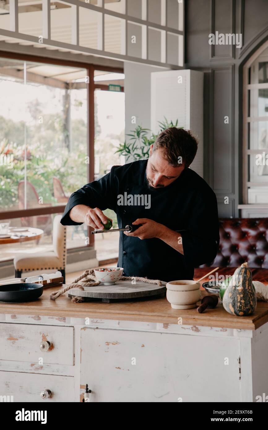 Concentrated man rubbing zest of fruit during cooking process at