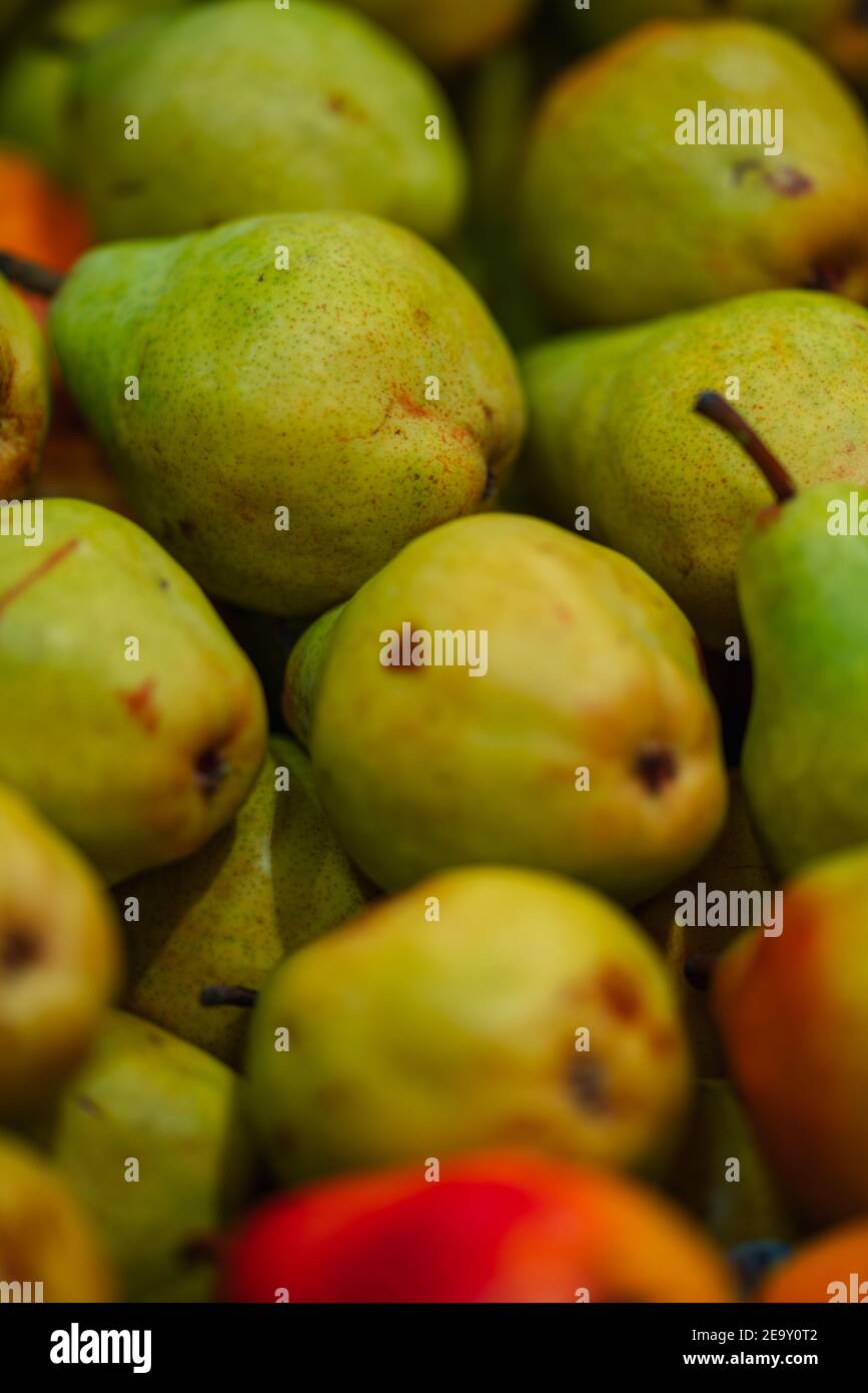 Vertical shot of ripe pears under the lights with a blurry background ...