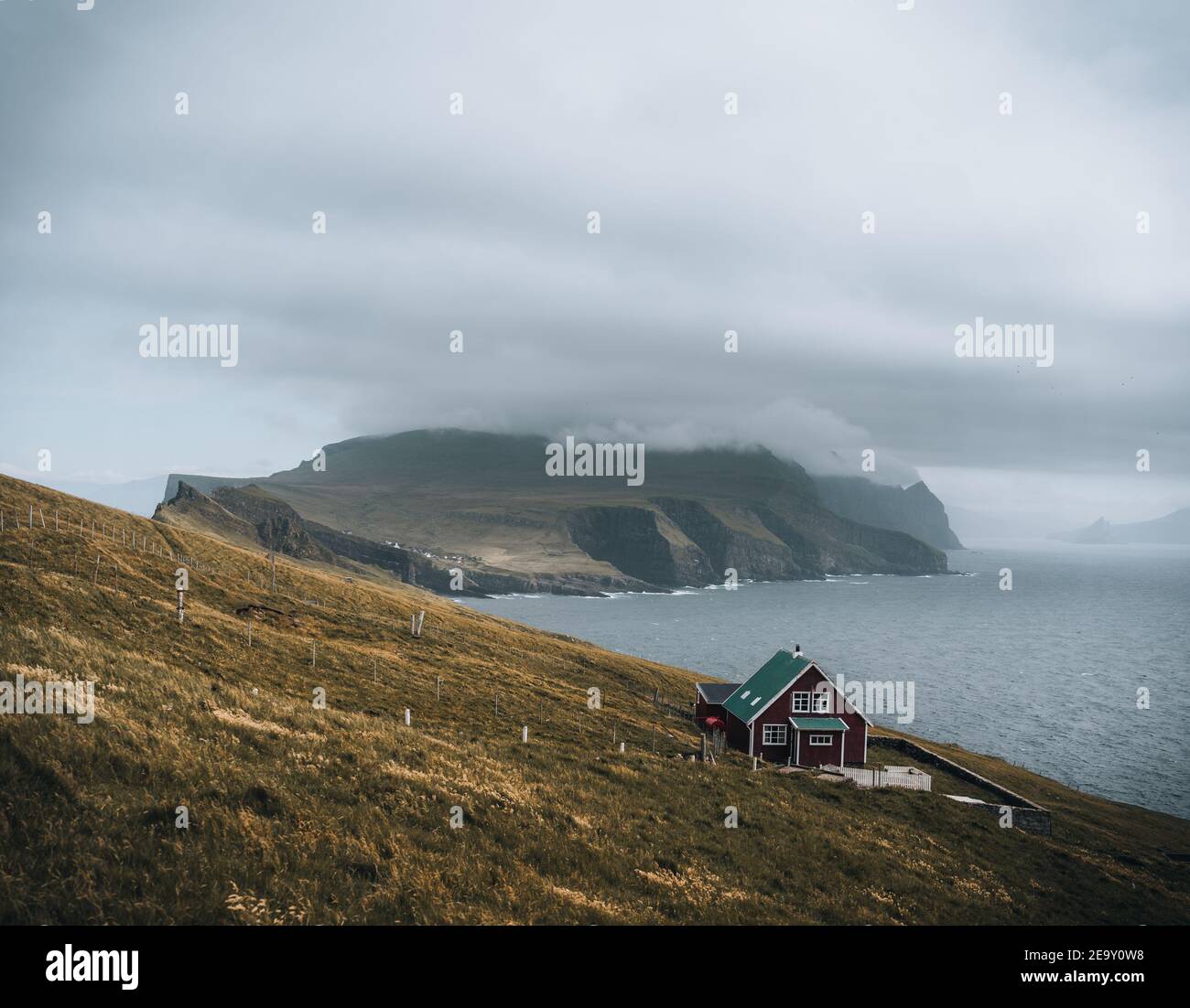 View Towards Lighthouse on the island of Mykines Holmur, Faroe Islandson a cloudy day with view towards Atlantic Ocean. Stock Photo