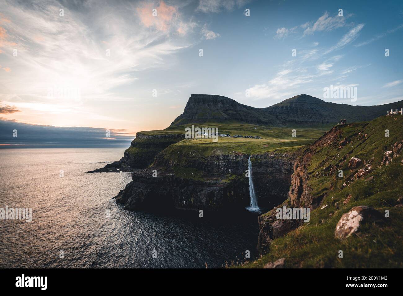 Gasadalur village and Mulafossur its iconic waterfall during summer with bluw sky. Vagar, Faroe Islands, Denmark. Rough see in the north atlantic Stock Photo