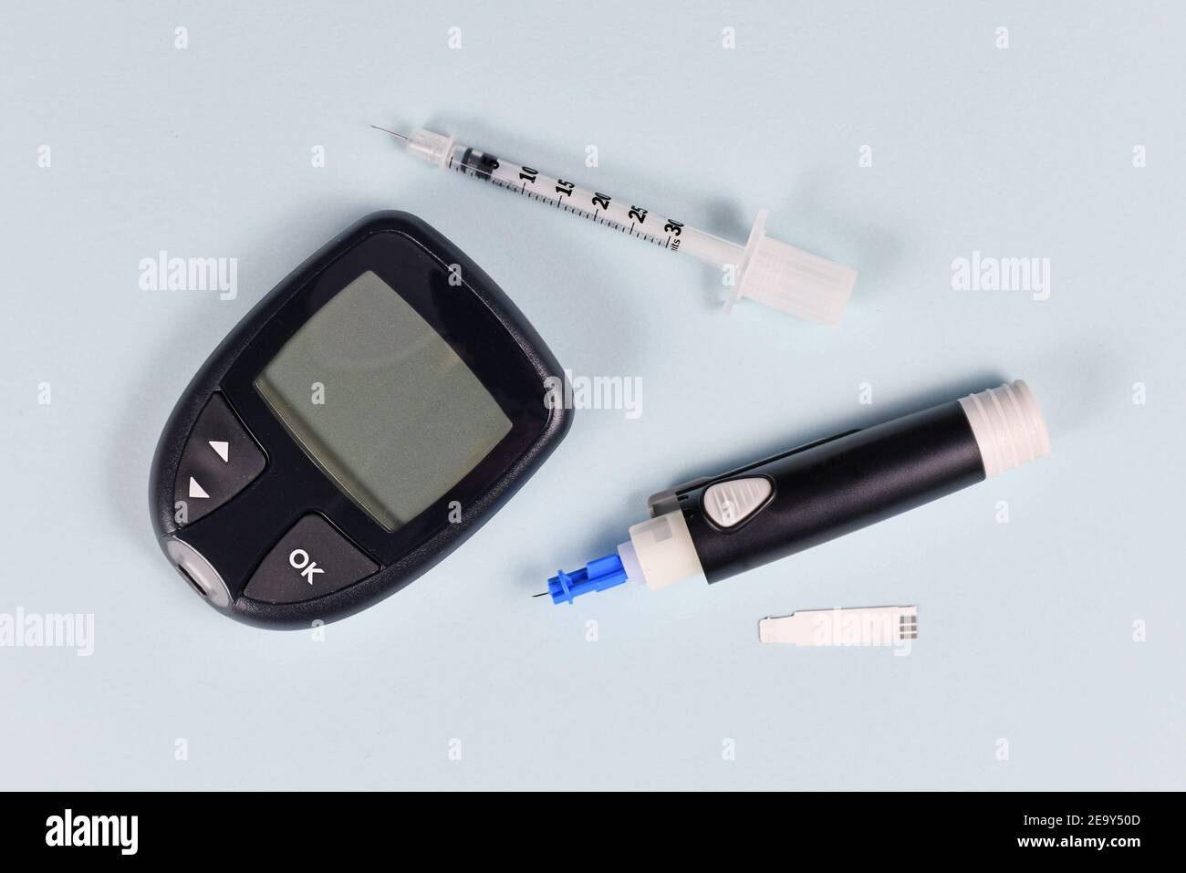 Equipment for diabetes treatment with blood glucose sugar meter, lancet, syringe and lancing device on blue background Stock Photo