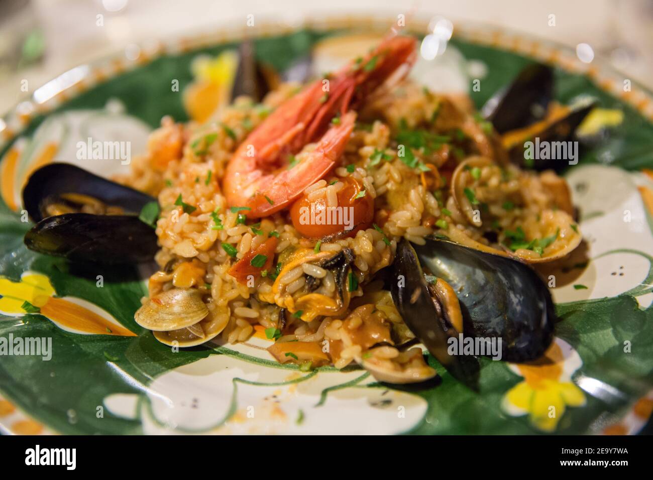 Italian food: seafood risotto with grilled prawn and mussels on a hand-painted ceramic plate of the island of Capri, Tyrrhenian sea, Italy Stock Photo