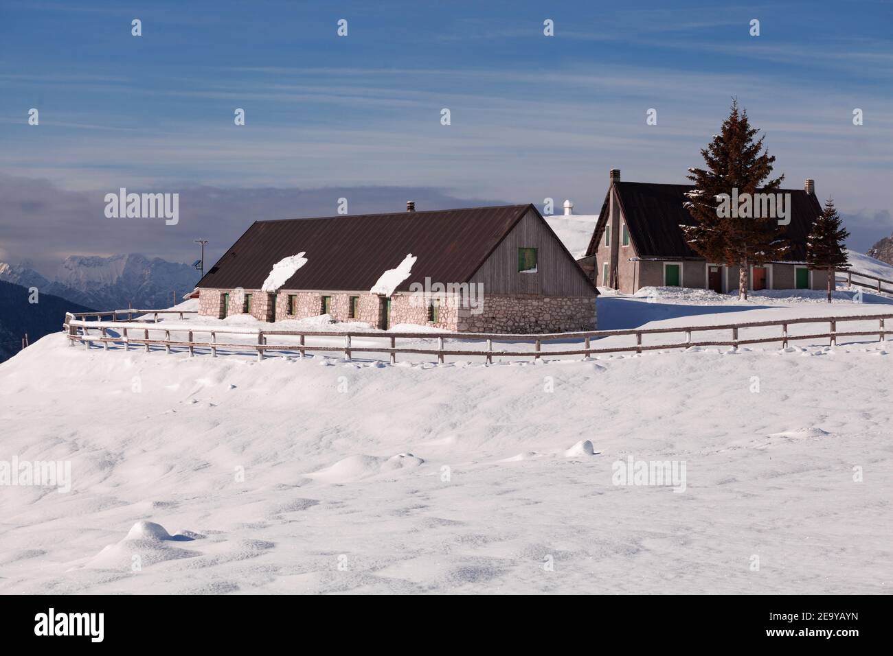 Mountain farm in winter with snowy surroundings and high mountain background Stock Photo