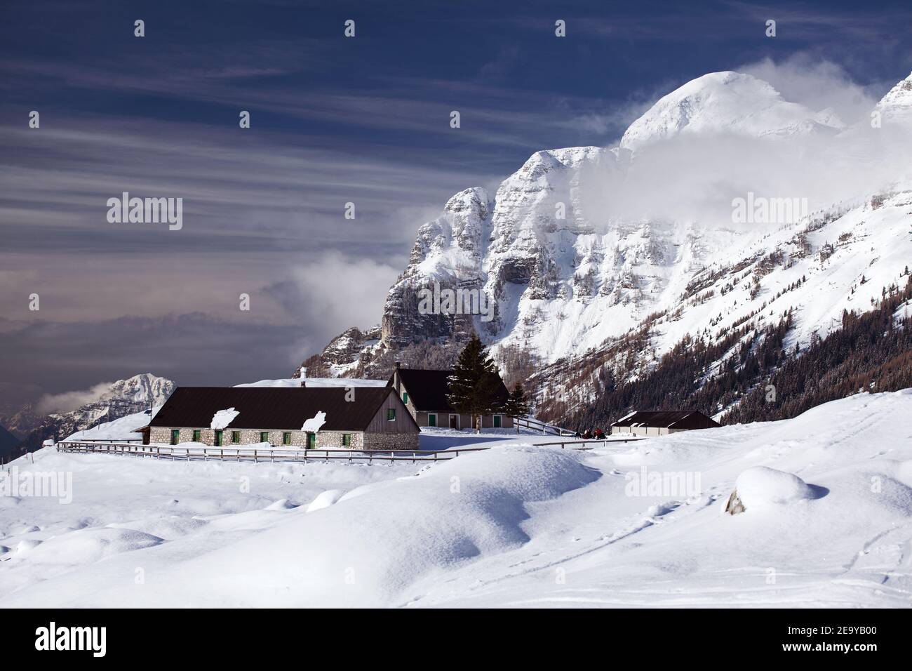 Mountain farm in winter with snowy surroundings and high mountain background Stock Photo