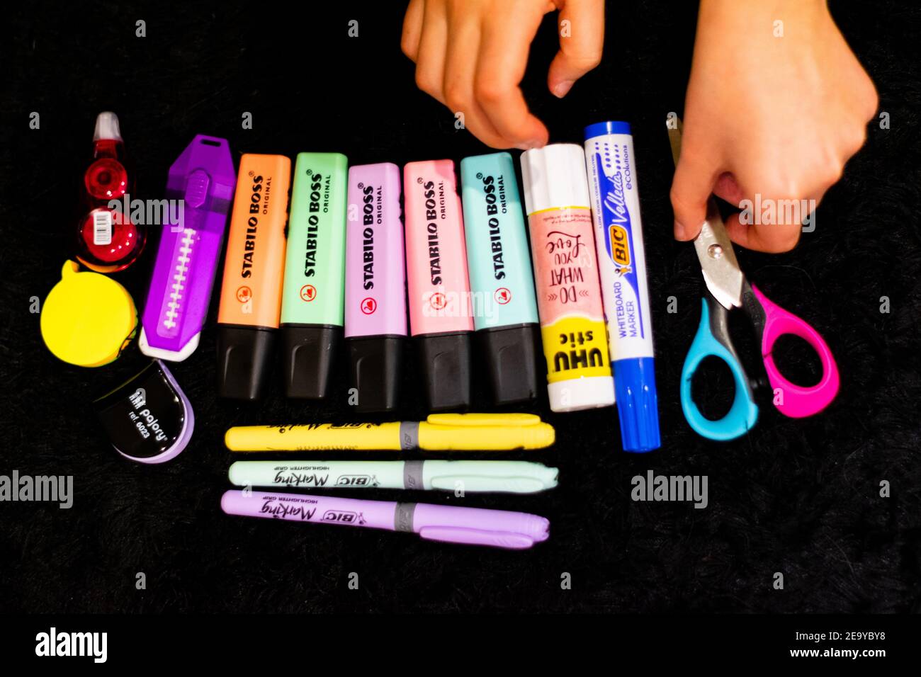 Children organizing School tools like stabilo boss, bic markers, scissors, pencil rubber for home schooling times and ready to go back to school. Returning to school. Stock Photo