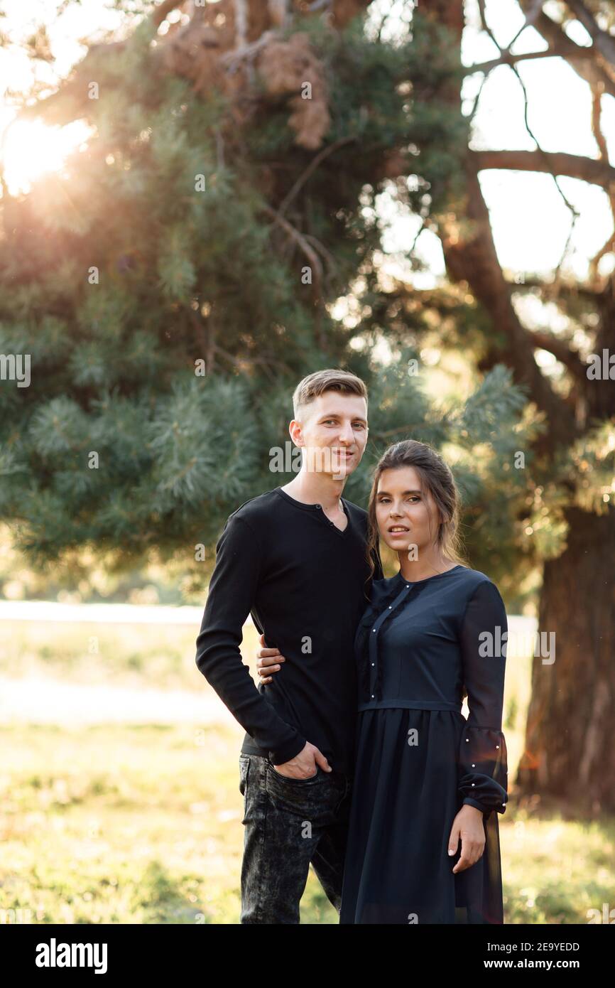 Cheerful young woman and man are hugging outdoors in summer park ...