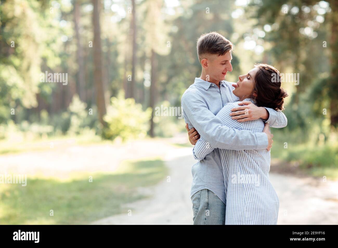 Cheerful young woman and man are hugging outdoors in summer park ...