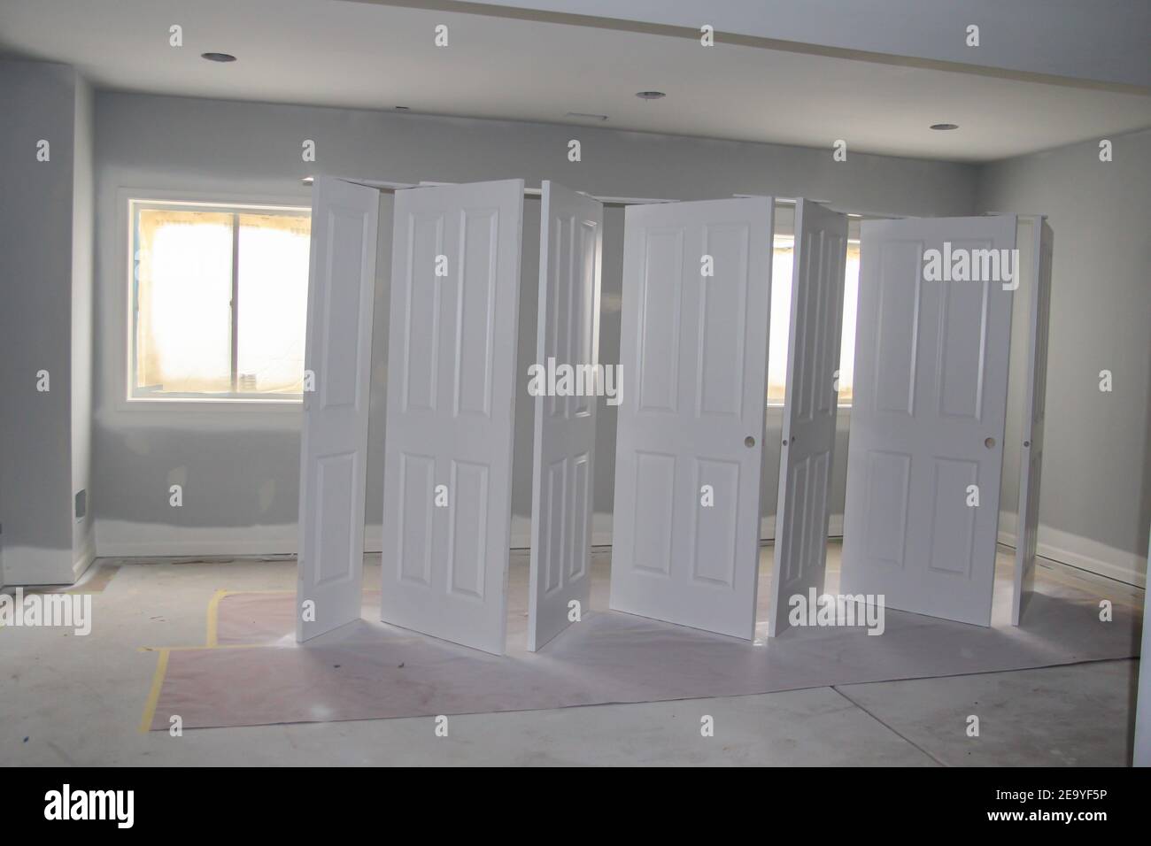 White painted four panel doors spray painted with airless sprayer in the basement with light coming in the windows. Stock Photo