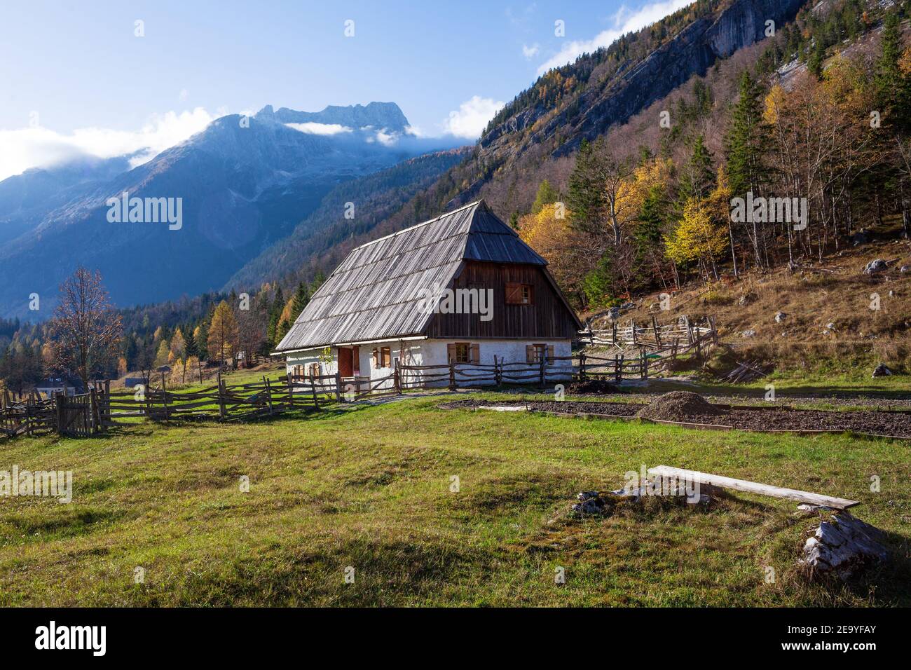 Traditional Trenta house in the July Alps with a wooden roof and an old wooden fence surrounding the house. Stock Photo