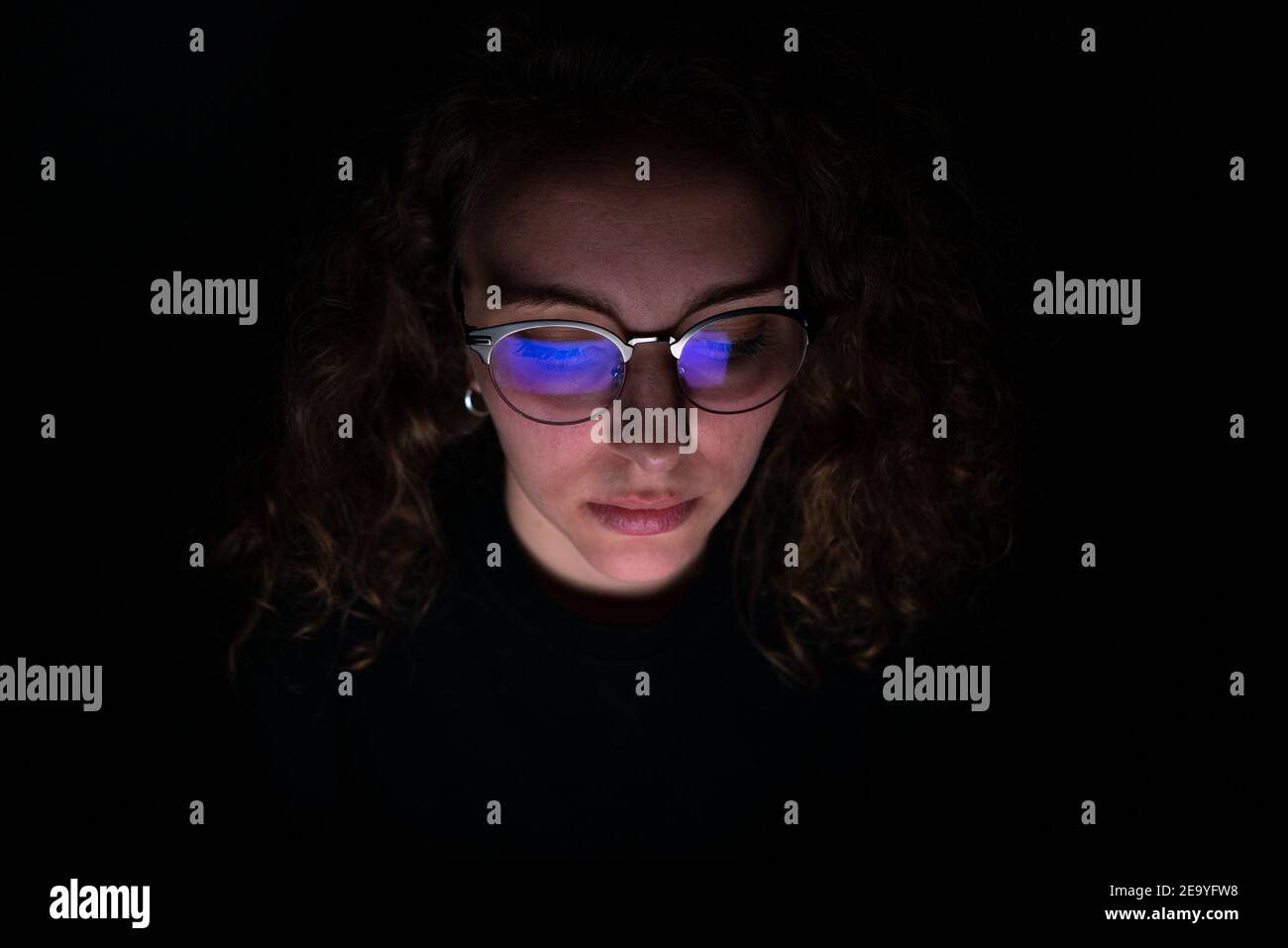 Computer screen reflected in the glasses of a woman who works at night ...