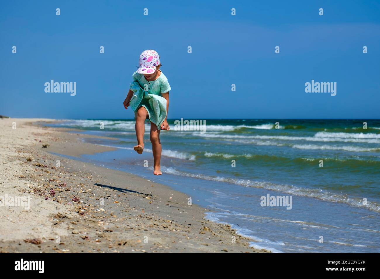 Baby girl skipping along the sea beach Stock Photo