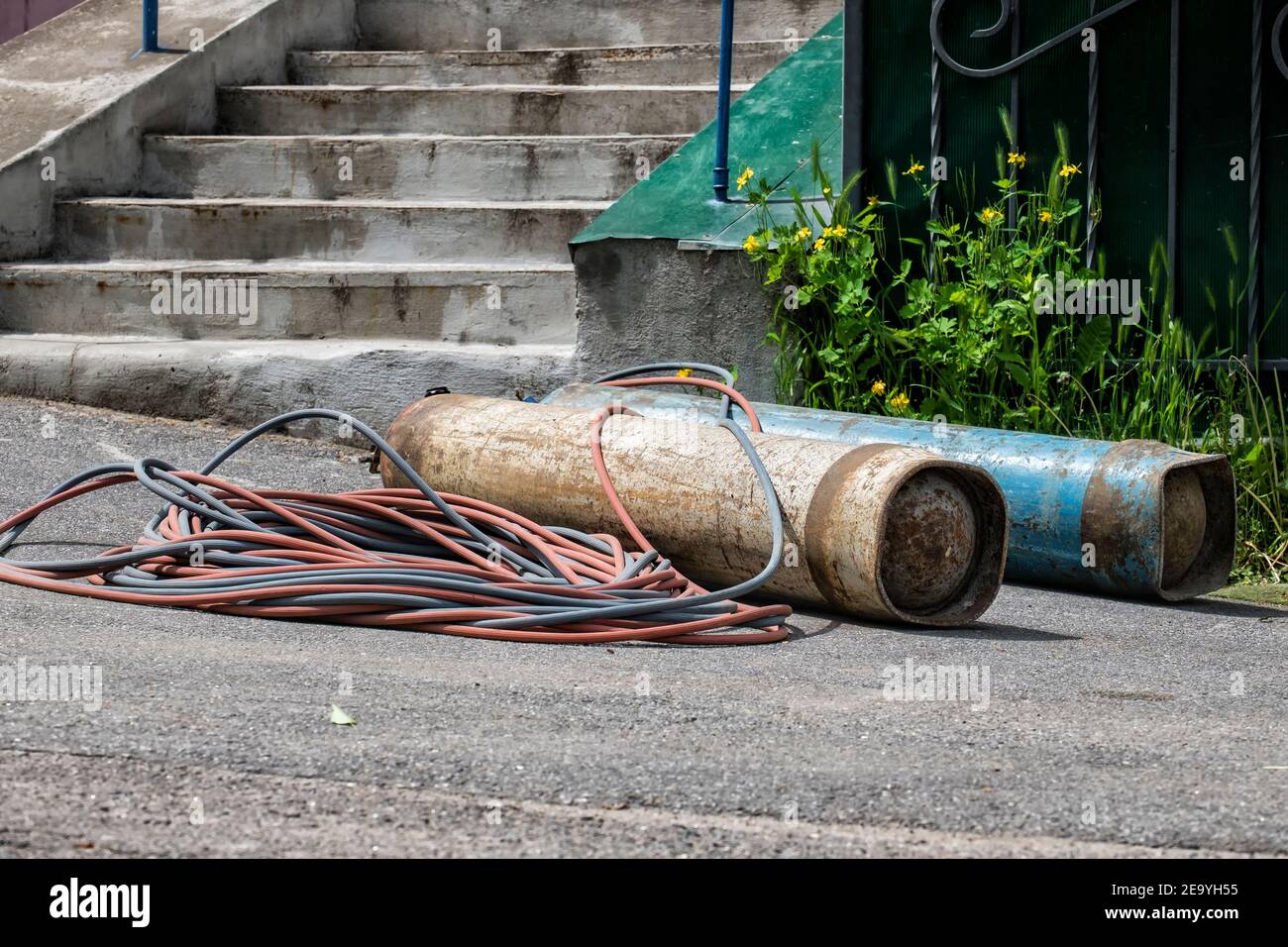 Old propane and oxygen cylinders for gas welding lie on the ground Stock Photo
