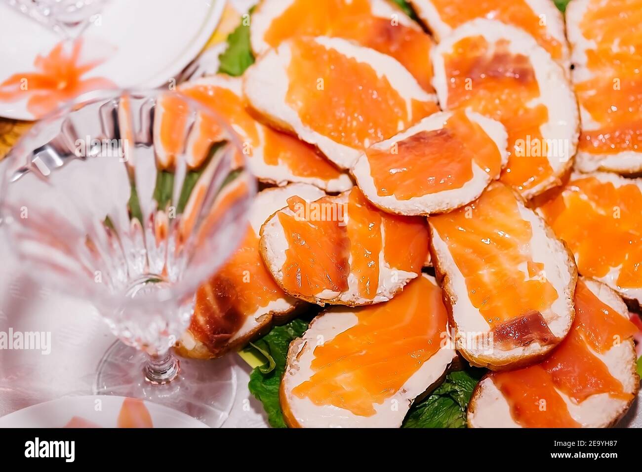 many sandwiches with butter and red fish lie on a plate near a crystal champagne glass Stock Photo