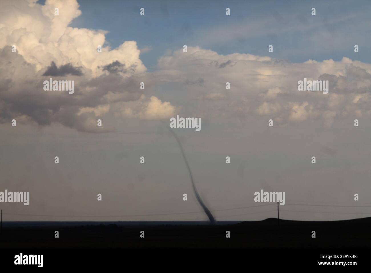 A peaceful landspout tornado sits nearly stationary over open land, providing an awesome