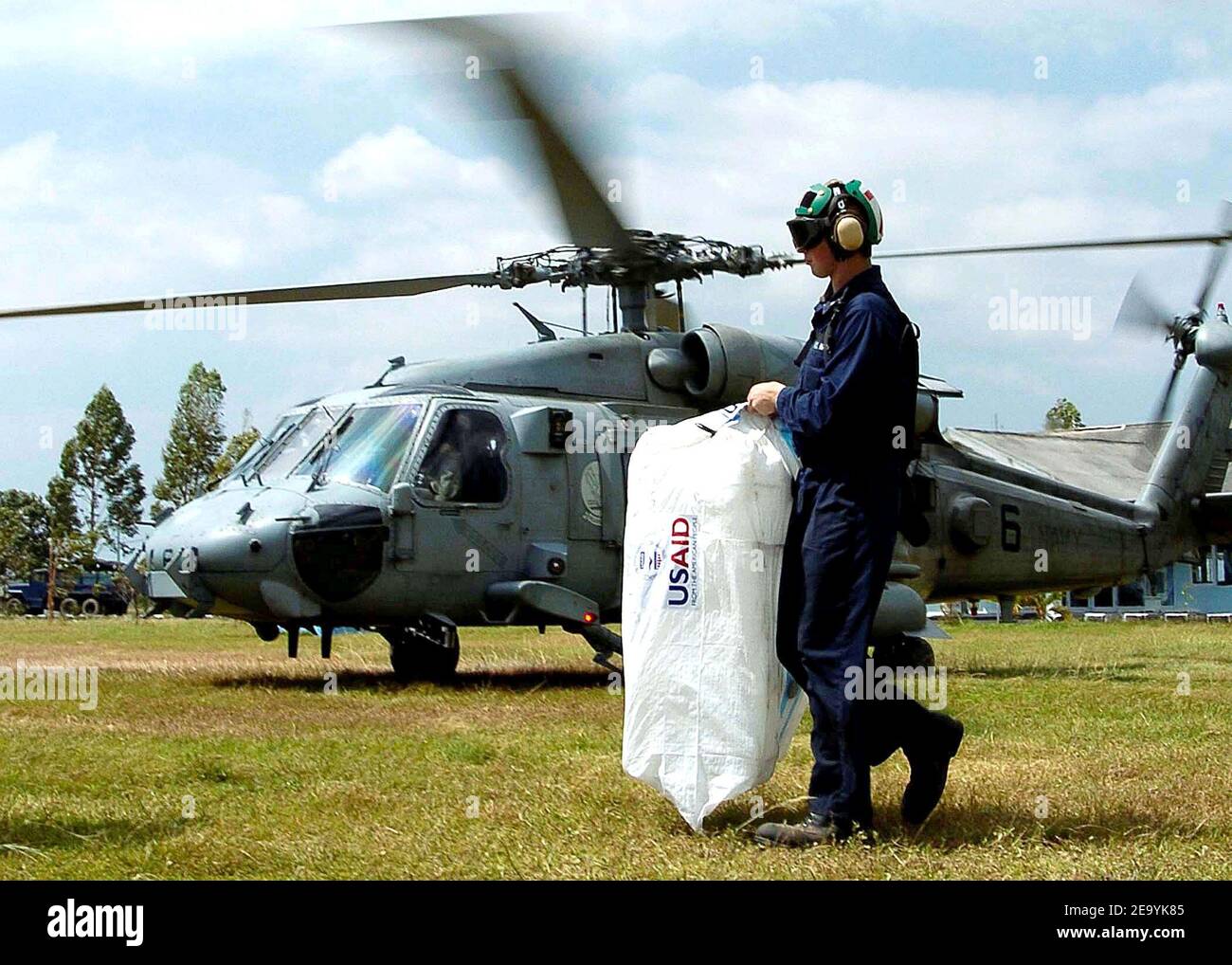 A Sailor carries a bag of empty water jugs to a waiting HH-60H Seahawk helicopter, assigned to the 'Golden Falcons' of Helicopter Anti-Submarine Squadron Two (HS-2), en route to USS Abraham Lincoln (CVN 72) to be filled with purified water. Helicopters assigned to Carrier Air Wing Two (CVW-2) and Sailors from Abraham Lincoln are supporting Operation Unified Assistance, the humanitarian operation effort in the wake of the Tsunami that struck South East Asia. Photo by Seth C. Peterson/USN via ABACA. Stock Photo