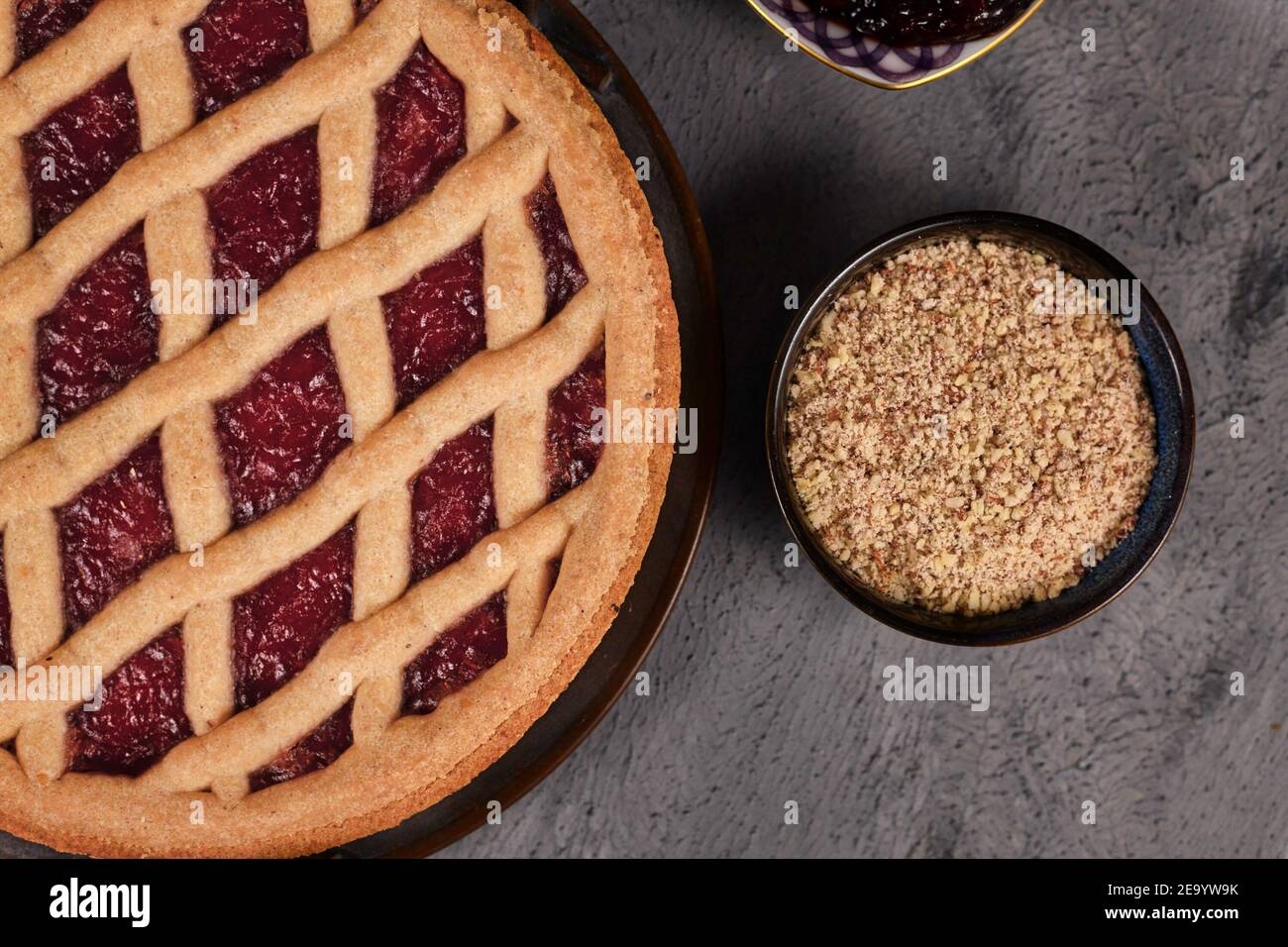 Close up of pie called 'Linzer Torte', a traditional Austrian shortcake pastry topped with fruit preserves and sliced nuts with lattice design next to Stock Photo