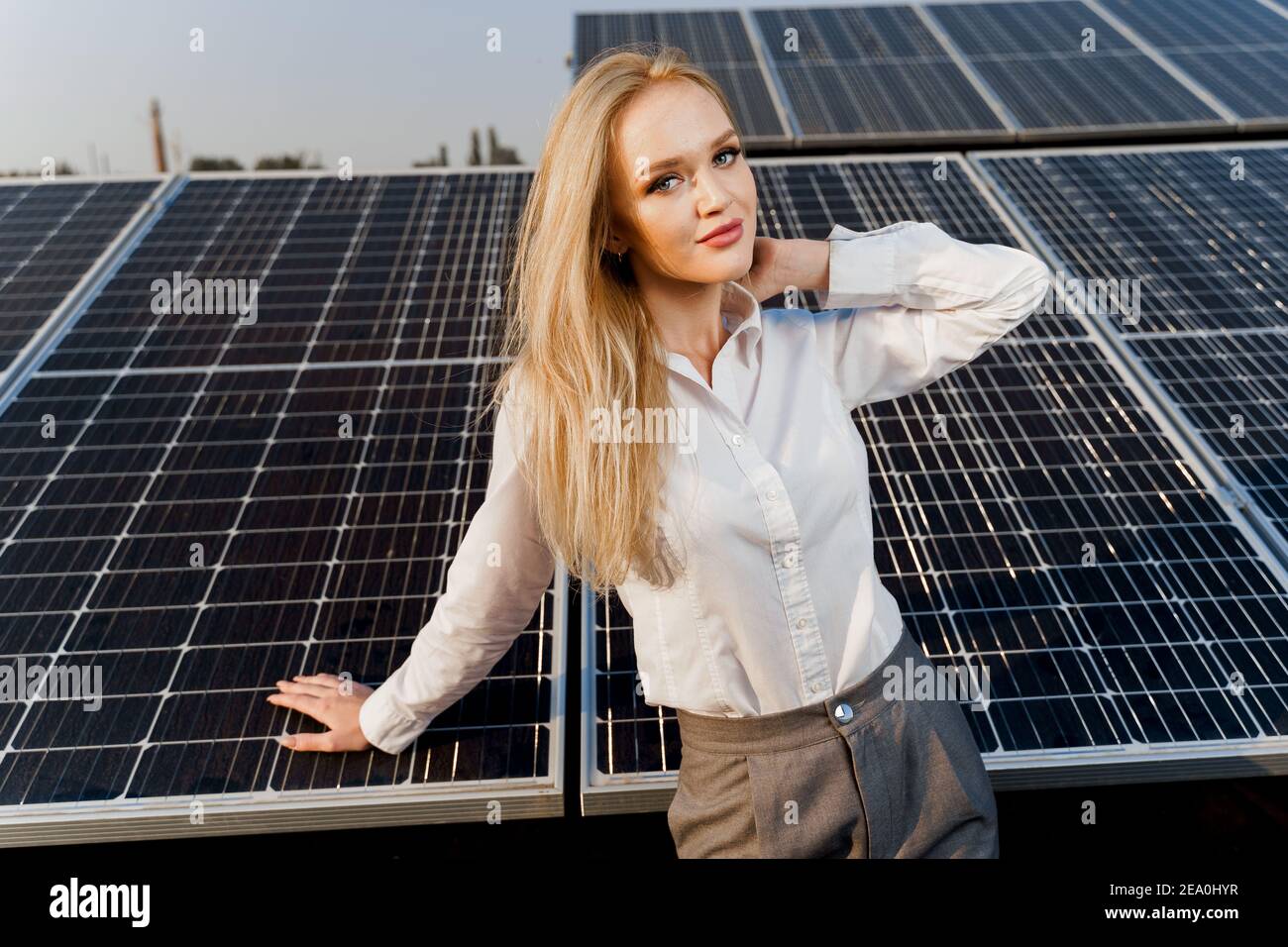 Blonde model with solar panels stands in row on the ground. Girl ...
