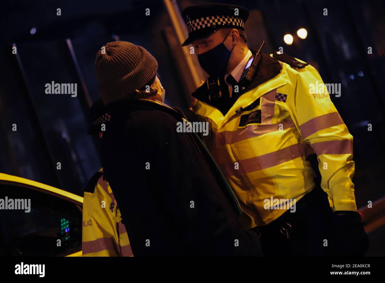 London, UK. 6th February, 2021. Candlelit vigil in remembrence of the lost trees at Euston Square, London as part of the Stop HS2 protest February 6th 2021. A police officer challenges a protestor Credit: Denise Laura Baker/Alamy Live News Stock Photo