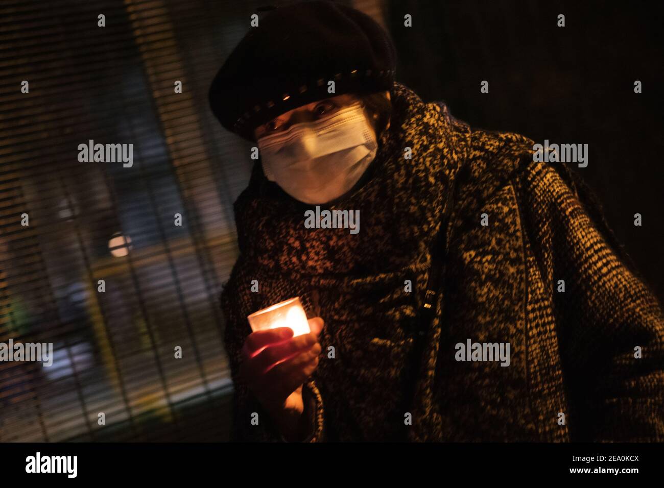 London, UK. 6th February, 2021. Candlelit vigil in remembrence of the lost trees at Euston Square, London as part of the Stop HS2 protest February 6th 2021. A woman with face covering and hat carries a candle Credit: Denise Laura Baker/Alamy Live News Stock Photo