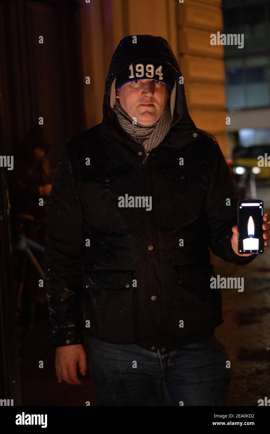 London, UK. 6th February, 2021. Candlelit vigil in remembrence of the lost trees at Euston Square, London as part of the Stop HS2 protest February 6th 2021. A man holds a candle image on his phone Credit: Denise Laura Baker/Alamy Live News Stock Photo