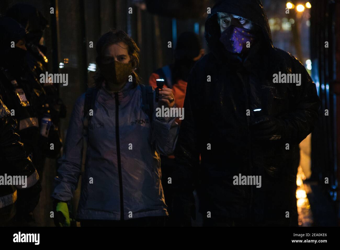 London, UK. 6th February, 2021. Candlelit vigil in remembrence of the lost trees at Euston Square, London as part of the Stop HS2 protest February 6th 2021. Women carry candles as the NET working for HS2 look on Credit: Denise Laura Baker/Alamy Live News Stock Photo