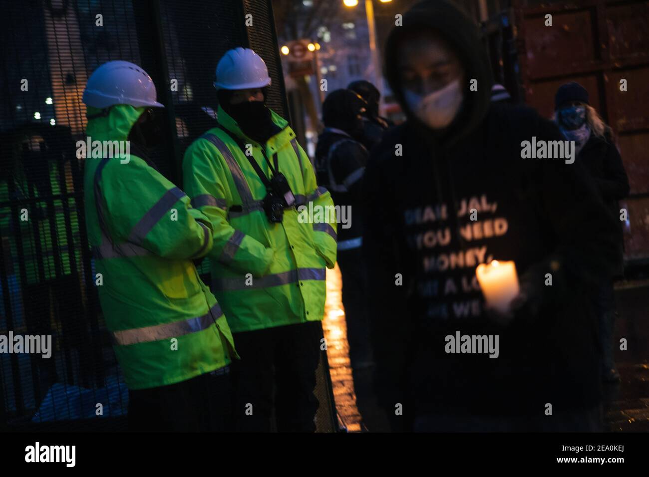 London, UK. 6th February, 2021. Candlelit vigil in remembrence of the lost trees at Euston Square, London as part of the Stop HS2 protest February 6th 2021. A woman carries a candle while security guards look on Credit: Denise Laura Baker/Alamy Live News Stock Photo