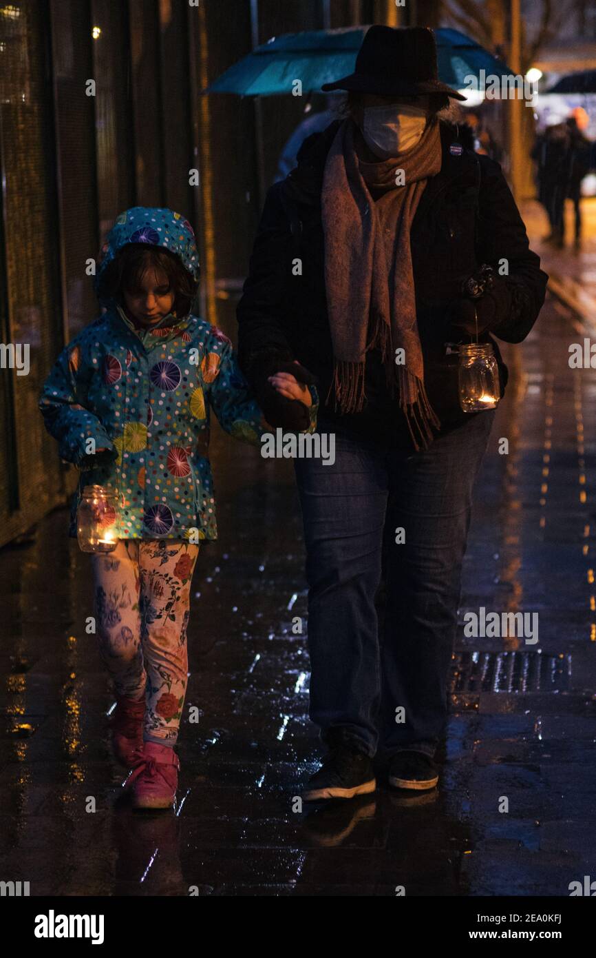 London, UK. 6th February, 2021. Candlelit vigil in remembrance of the lost trees at Euston Square, London as part of the Stop HS2 protest February 6th 2021. A mother and child walk with heads bowed holding candles Credit: Denise Laura Baker/Alamy Live News Stock Photo