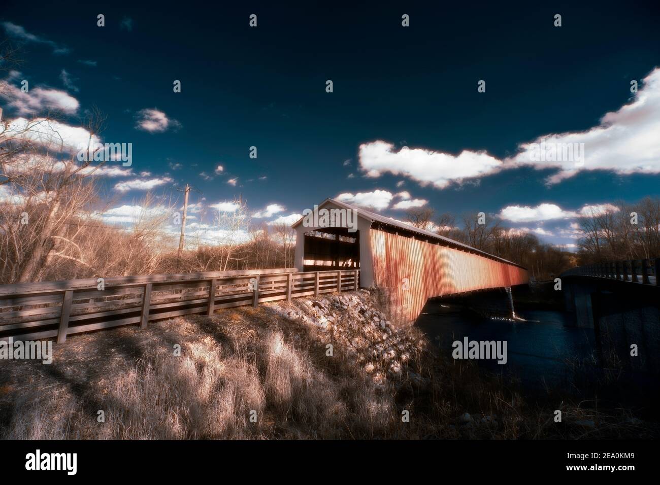The covered bridge in Shieldstown, IN imaged in false color infrared light on a bright winter afternoon.  Sky is deep blue and clouds are fluffy. Stock Photo