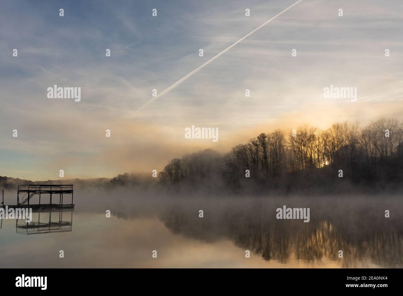 Fog on the surface of the water at sunrise with a blue and orange sky on Lake Lanier outside of Atlanta, Georgia with a dock; landscape view Stock Photo