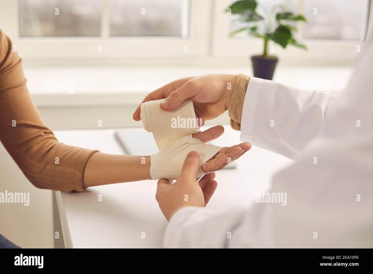 Doctor gently rewinds the patient's hand with an elastic bandage in the medical office. Stock Photo