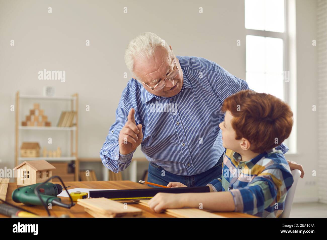 Wise grandfather reminds grandson of safety precautions when working at the workshop Stock Photo