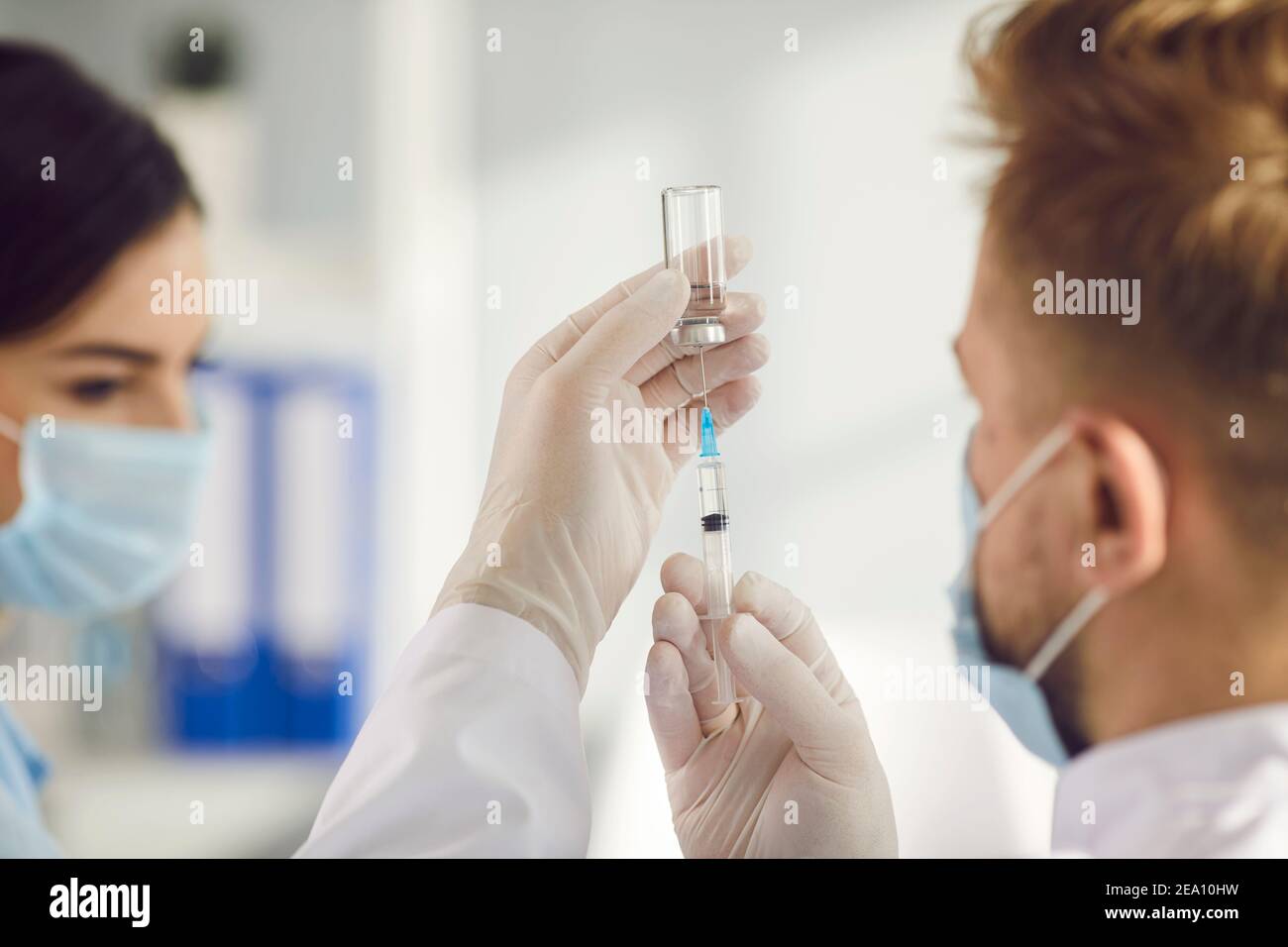 Close-up of filling syringe with vaccine from ampule in man doctors hands before vaccinating Stock Photo