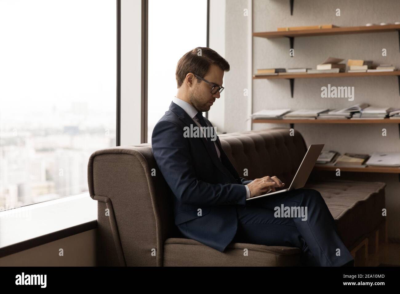 Young man visitor sitting on sofa in office using pc Stock Photo