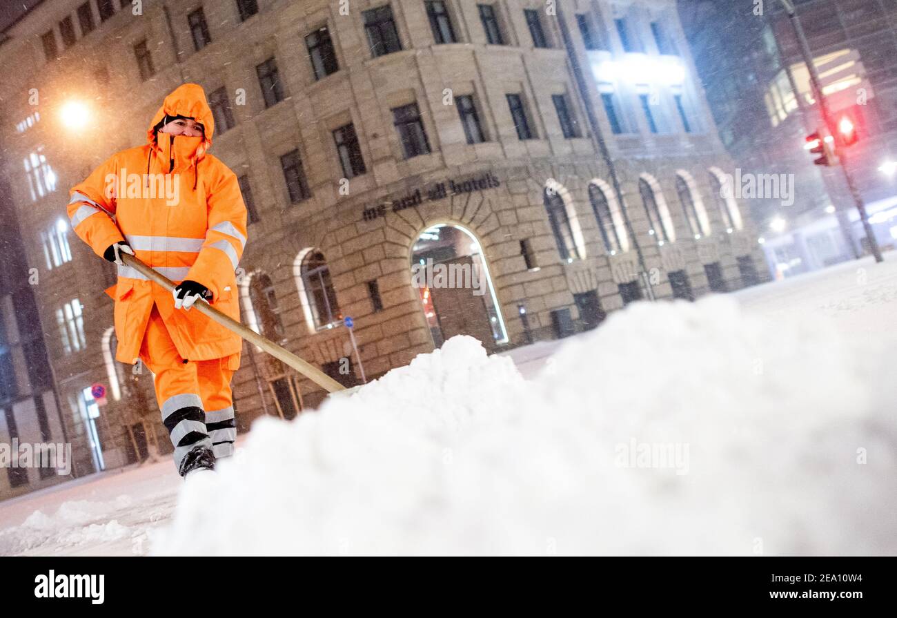 Hanover, Germany. 07th Feb, 2021. An employee of aha Zweckverband Abfallwirtschaft Region Hannover clears a pavement at Aegidientorplatz of snow and ice during snowfall. Credit: Hauke-Christian Dittrich/dpa/Alamy Live News Stock Photo