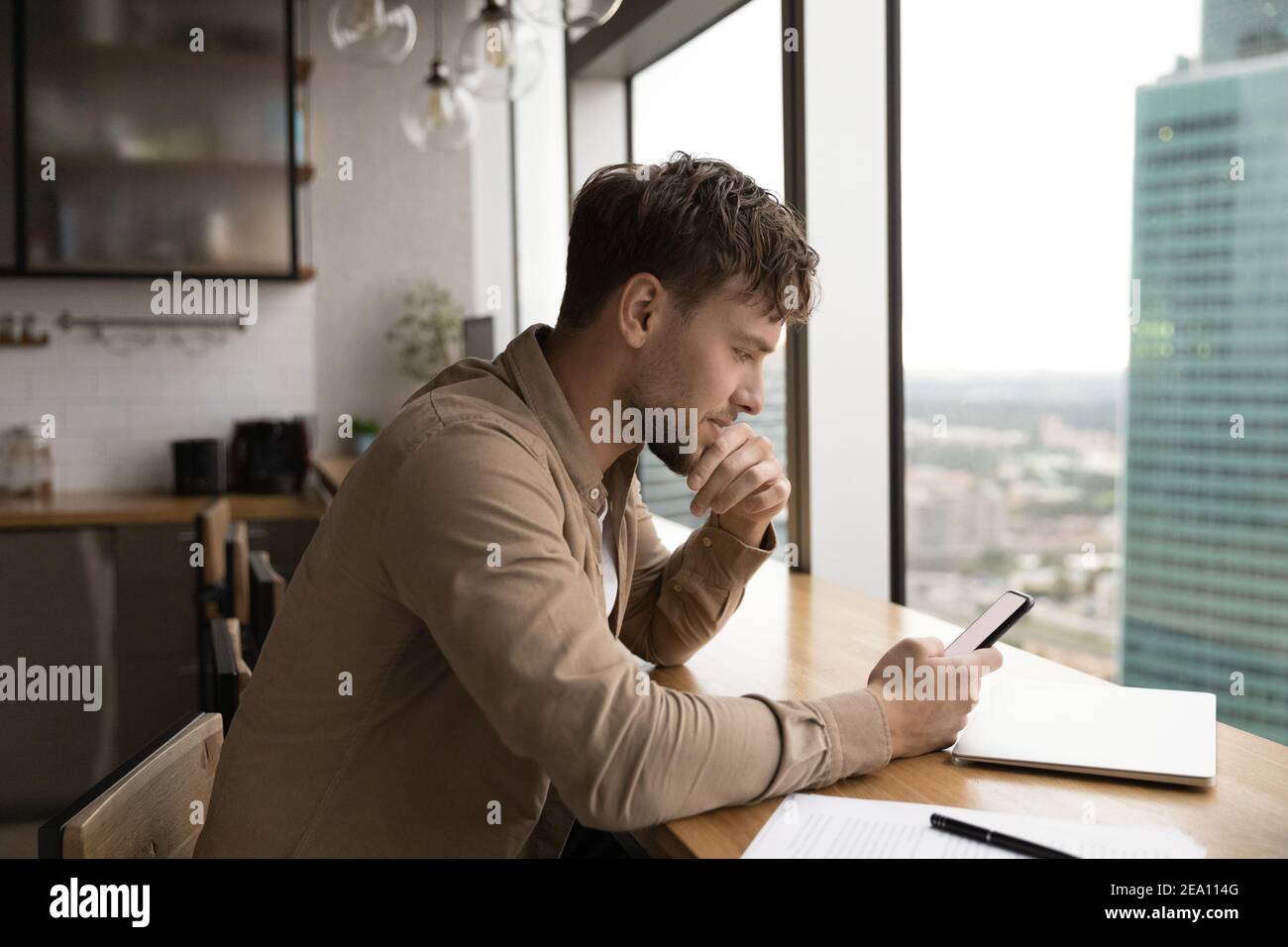 Businessman sit by window at kitchen read message on phone Stock Photo