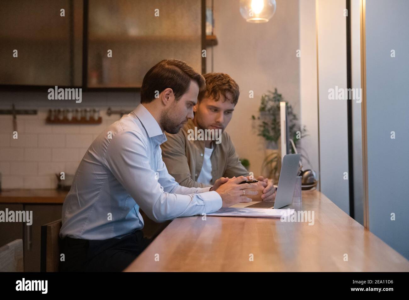 Young man analyse electronic report mistakes with skilled male colleague Stock Photo