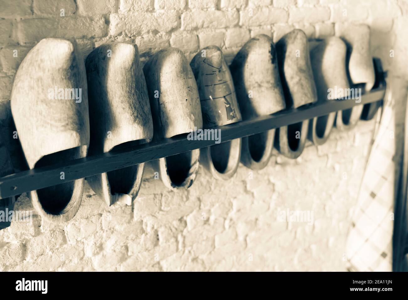 Row of Dutch clogs in rack on wall in selective focus and monochrome old-world effect. Stock Photo