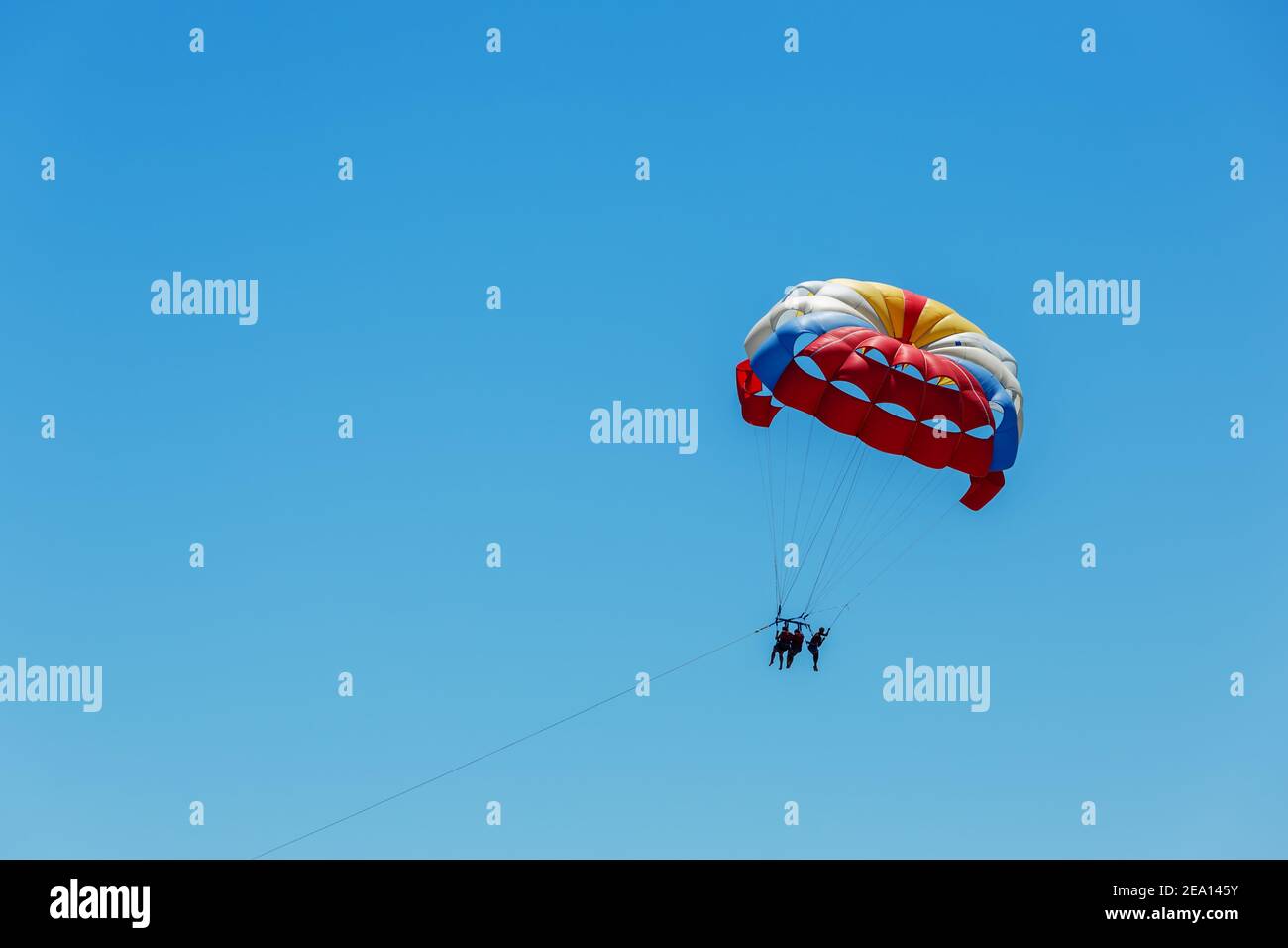 Paratroopers fly high in the blue sky. Amusement hire of parachutes