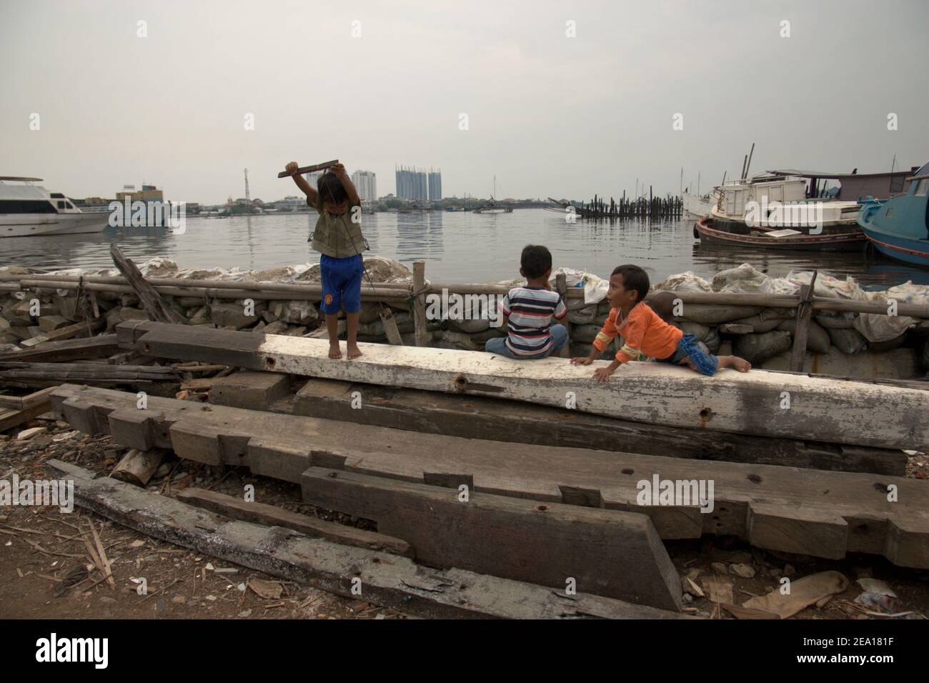 A group of children having a recreation behind the coastal protection structure protecting their neighbourhood from sea water floods in Muara Baru area, in the coastal area of Jakarta, Indonesia. Archival photo. Stock Photo