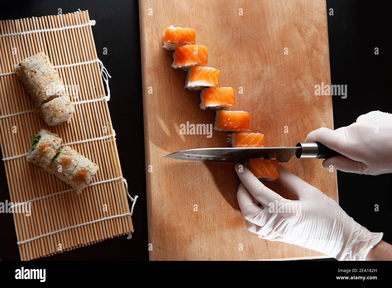 https://c8.alamy.com/comp/2EA182H/knife-in-hand-cuts-the-roll-closeup-on-a-wooden-board-2EA182H.jpg