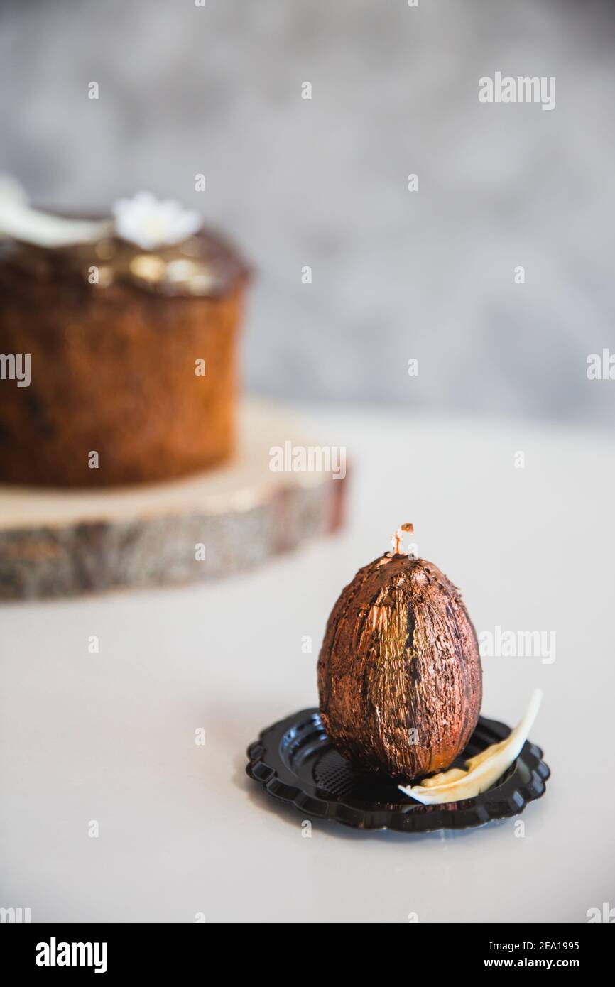 Handmade chocolate with gold easter egg with easter cake on background. Close-up, copy spase Stock Photo