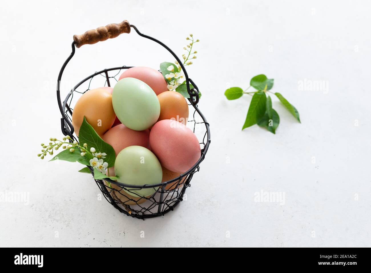Basket with colorful Easter eggs, spring flowers on white background Stock Photo
