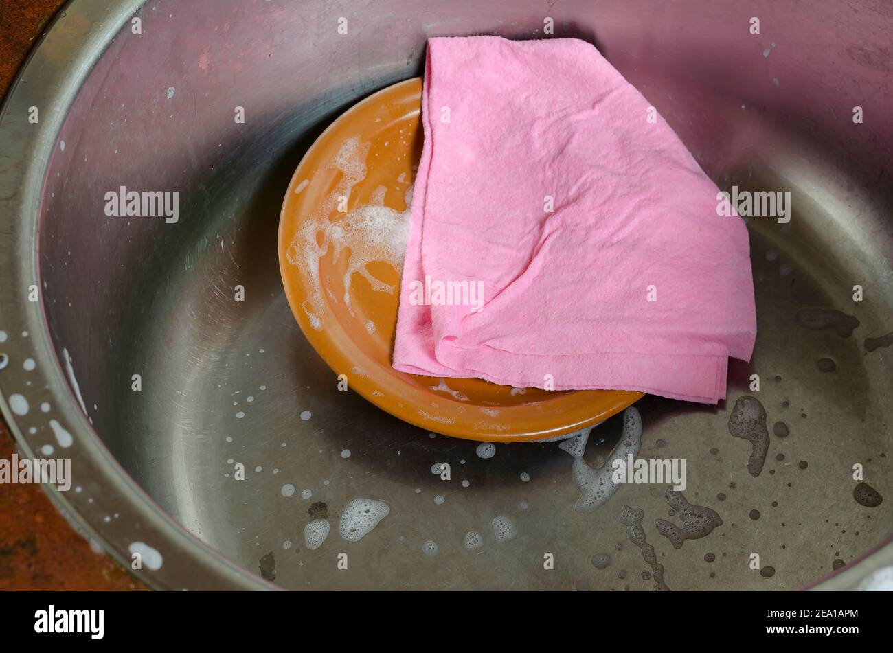 A pink viscose dish cloth rests on top of the kitchen faucet. Metal sink  with foam. Cleaning, washing dishes, household chores. Close-up, selective  fo Stock Photo - Alamy