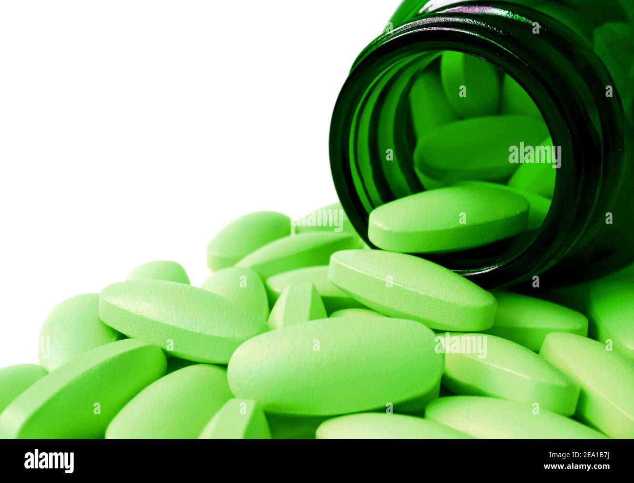 Oval shaped lime green tablets poured from dark green glass bottle on