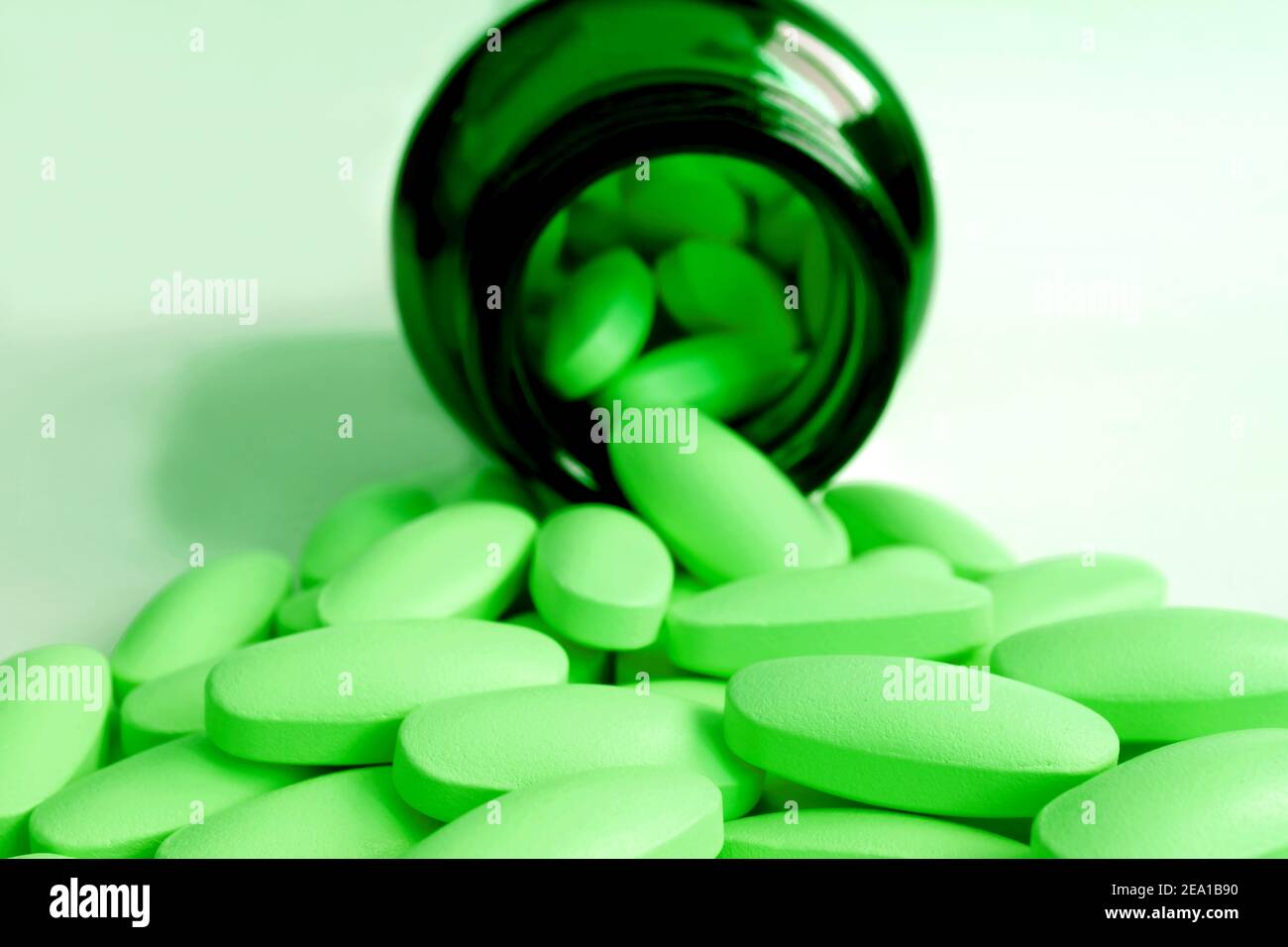 Bright Lime green pills poured from dark green glass bottle on the table Stock Photo