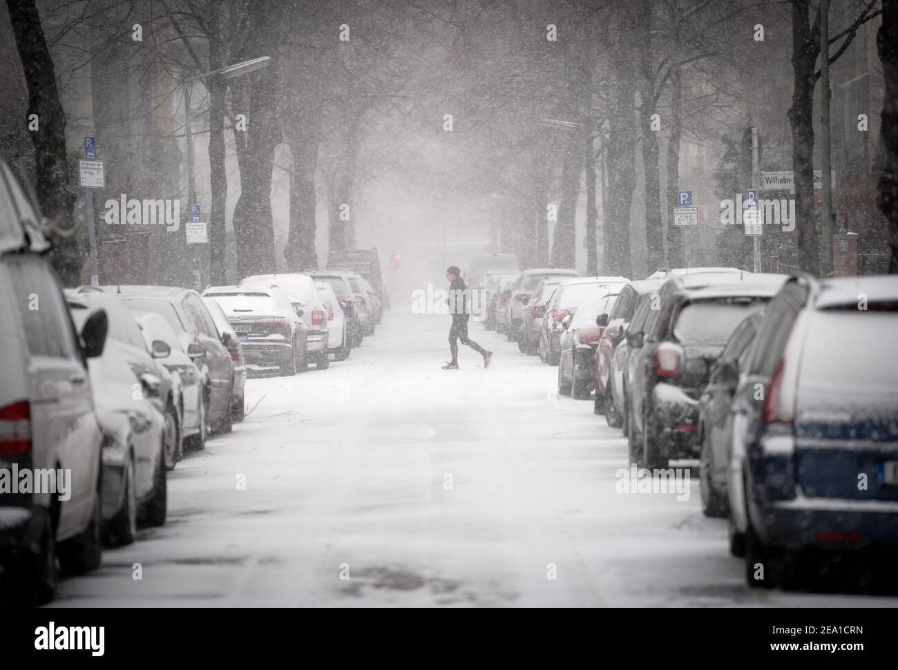 Berlin, Germany. 07th Feb, 2021. A jogger runs across a street in Berlin-Friedenau in heavy snow. Credit: Kay Nietfeld/dpa/Alamy Live News Stock Photo