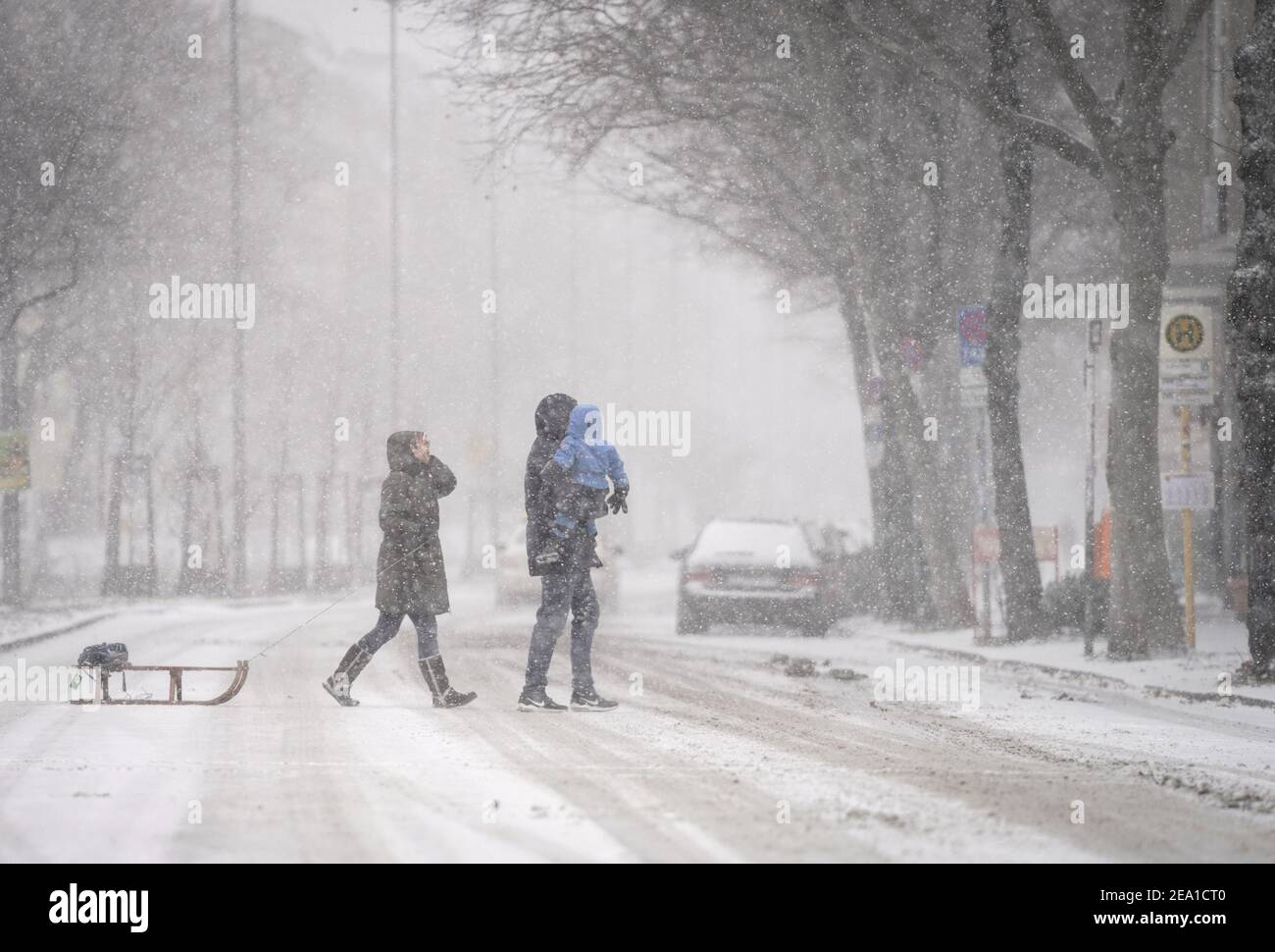 Berlin, Germany. 07th Feb, 2021. Passers-by walk along a street in Berlin-Friedenau with a toboggan in the thick snow. Credit: Kay Nietfeld/dpa/Alamy Live News Stock Photo