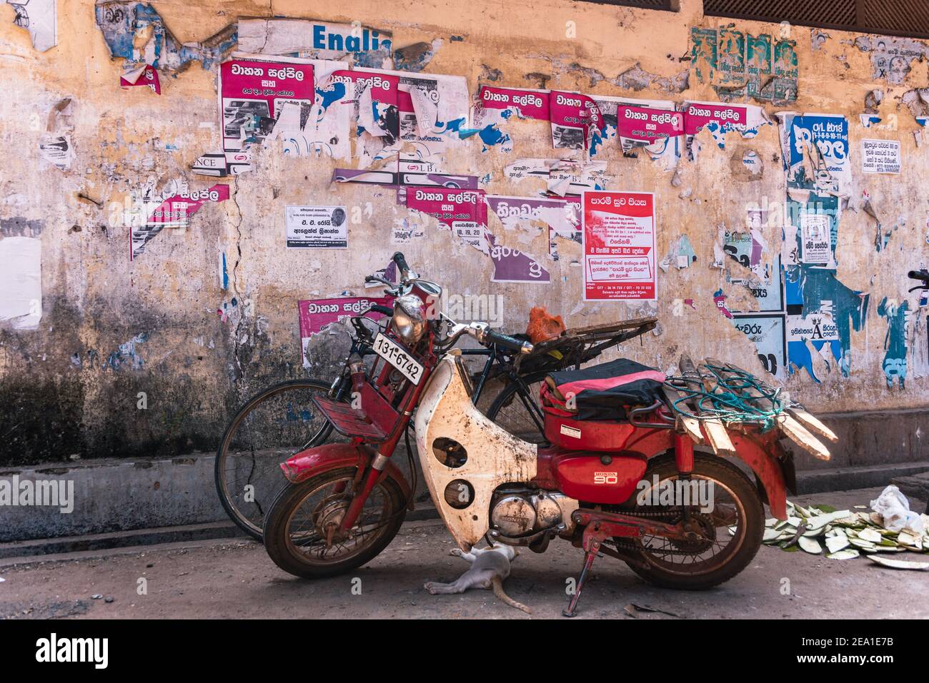 Motor cycle  in front of an Old torn poster paper scraps texture on a yellow street wall Stock Photo