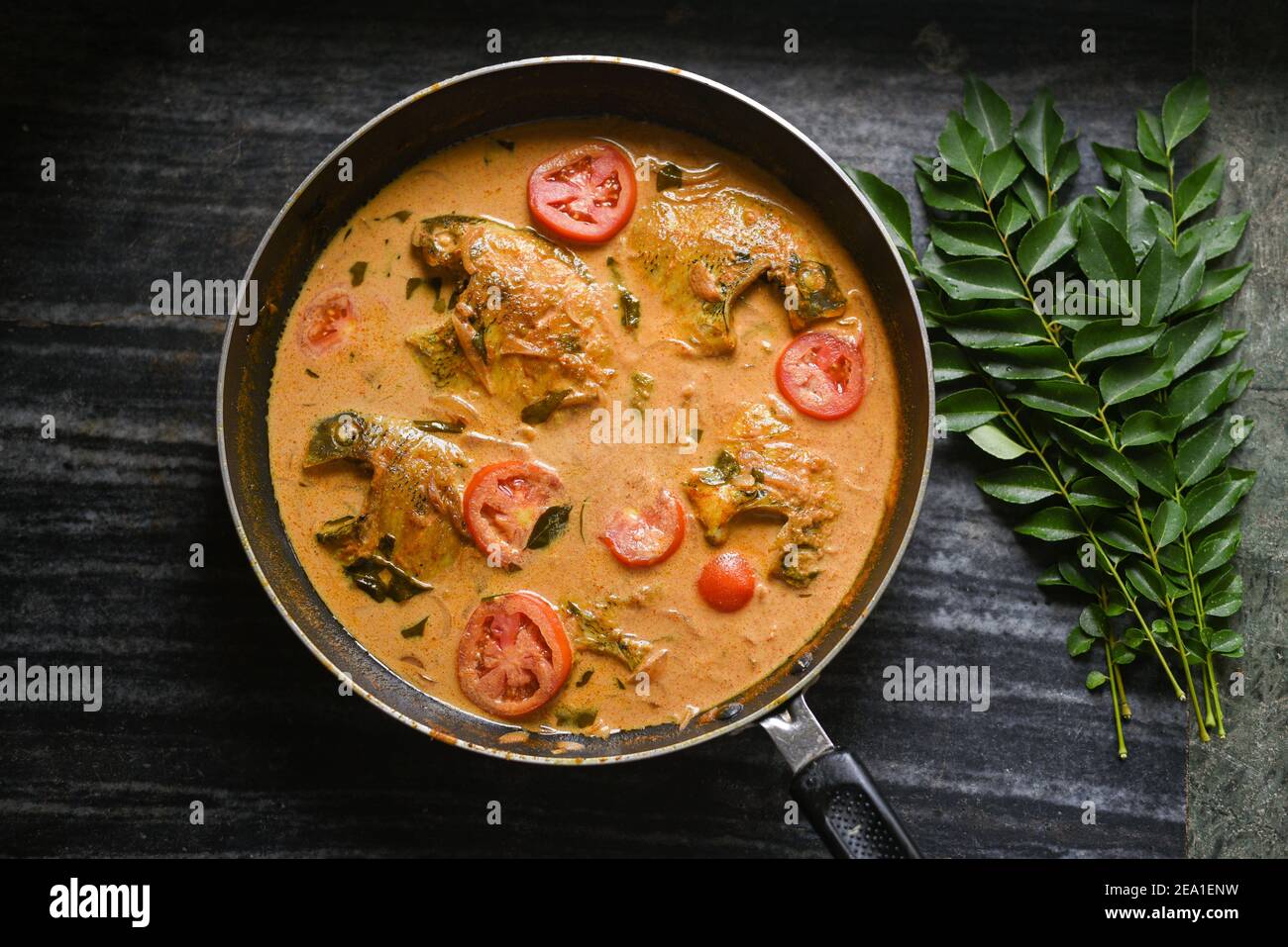 Top view spicy Kerala Style Fish curry stew and Appam Fish Molee Meen Moilee Indian food. Fish curry with coconut milk red chili, curry leaf, tomato. Stock Photo