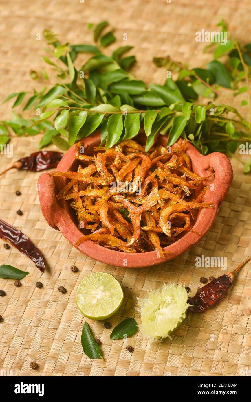 Top view spicy hot anchovy Kerala fish curry. Indian food. Woman hand
